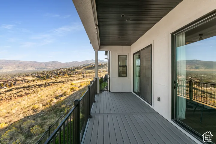 Outdoor deck with composite decking, black metal railings, and a mountain backdrop