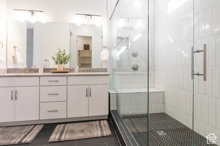 Dual vanity with a stone countertop, white cabinetry, and brushed nickel hardware