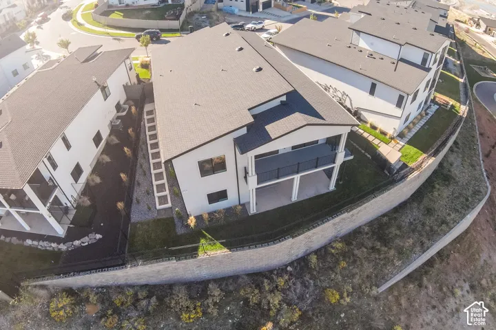 Back of the home residence featuring a private balcony, covered patio,  manicured lawn, and step on the side of the home.