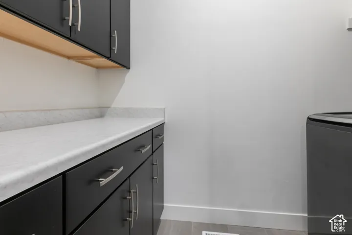 Black cabinetry with brushed nickel hardware, light-toned countertop, and light wood-finish shelving