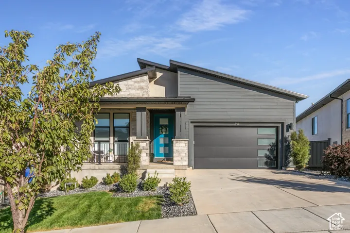Modern exterior with a contrasting architectural roofline, stone and horizontal siding facade, and a turquoise entry door