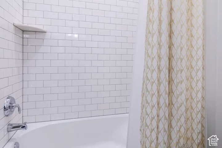 Bathtub with subway tile surround, integrated corner shelf, and polished chrome fixtures