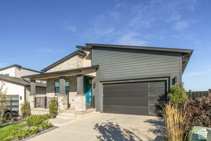 Modern architectural design featuring varied siding, a covered porch, stone accents, and an integrated garage