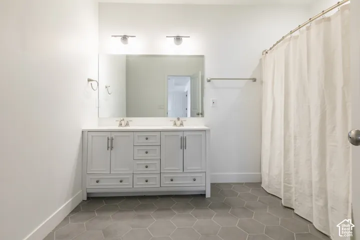 Double vanity with undermount sinks, hexagonal floor tiles, and dual wall-mounted light fixtures