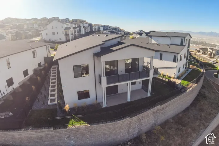 Multi-level contemporary residence featuring an upper-level balcony, a lower-level patio, and a terraced retaining wall