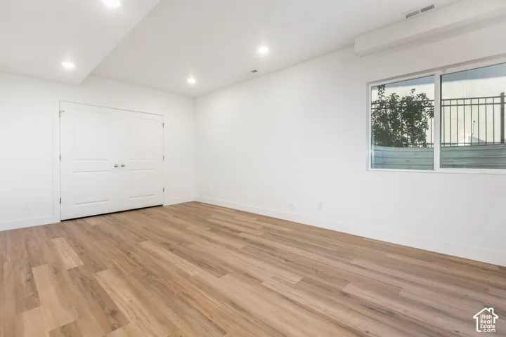 Recessed lighting, wood-finish flooring, white double doors, and a large sliding window with a black metal railing