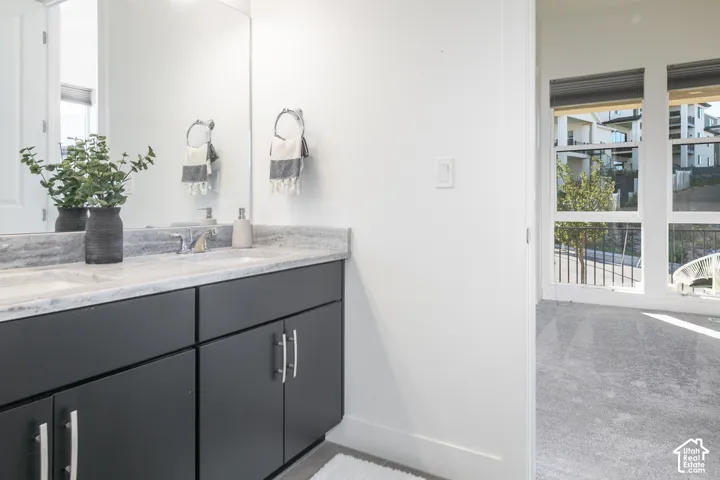 Modern bathroom featuring a dark cabinetry vanity with dual sinks, polished stone countertop, and chrome fixtures