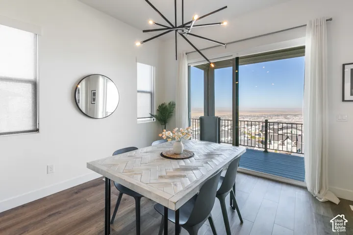 Spacious room featuring wood-finish flooring, a modern linear chandelier, and ample natural light from multiple windows