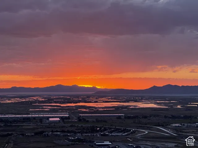 Expansive distant mountain range and a striking sunset horizon with vibrant orange and red hues