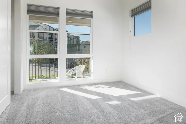 Bright corner room flooded with natural light through expansive dual French doors and transom window, featuring polished concrete flooring and roller shades