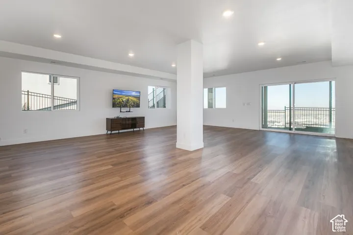 Spacious open-concept room featuring wood-finish flooring, recessed lighting, and multiple windows