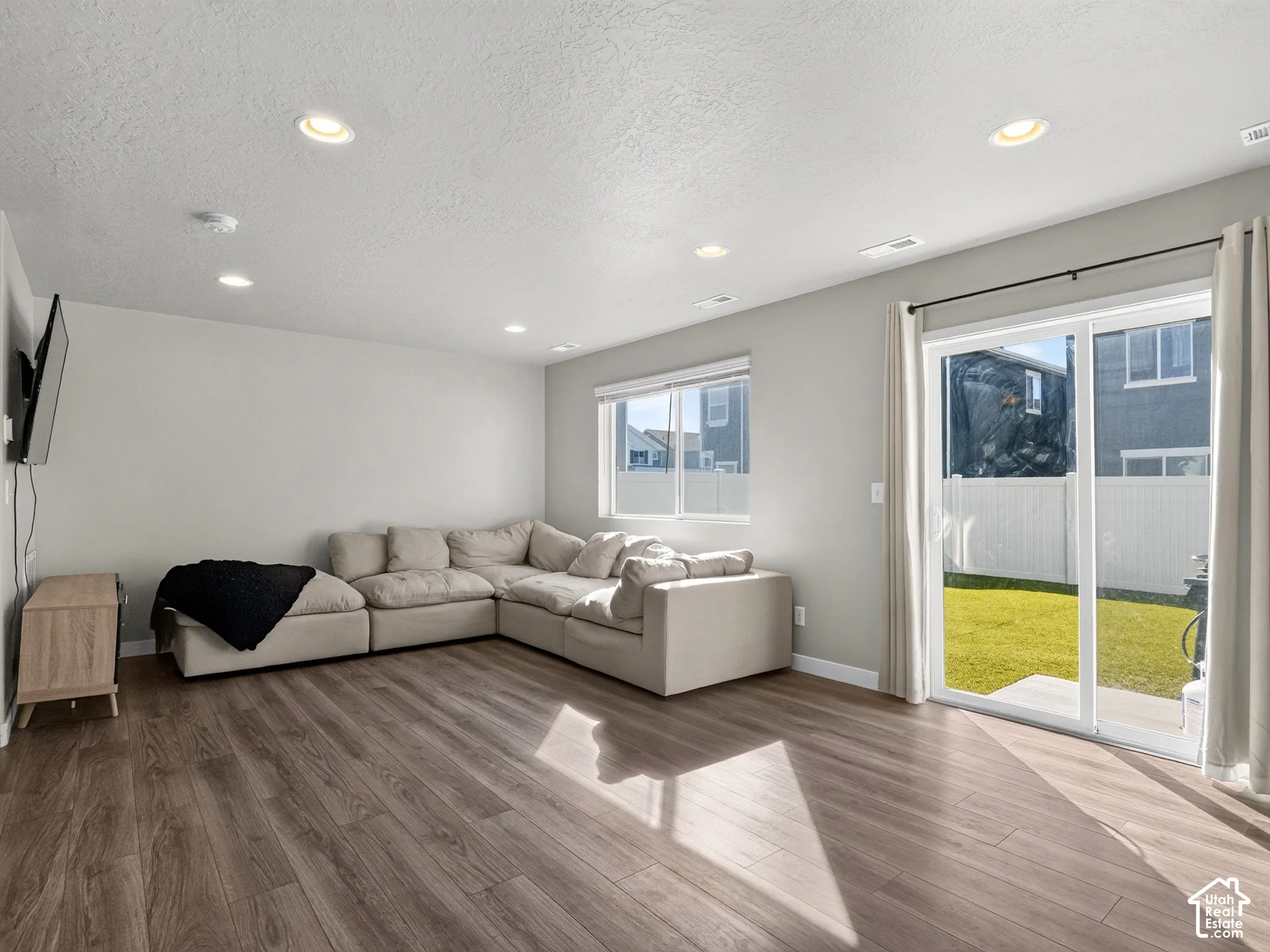 Wood-finish flooring, recessed lighting, and a sliding glass door providing exterior access