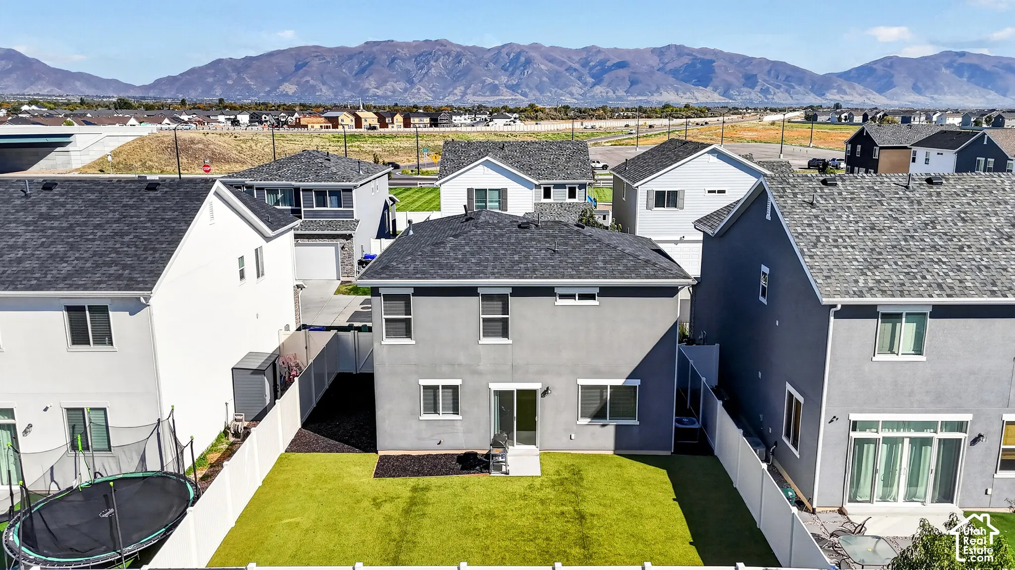 Fenced backyard featuring artificial turf, a concrete patio, and a sliding glass door