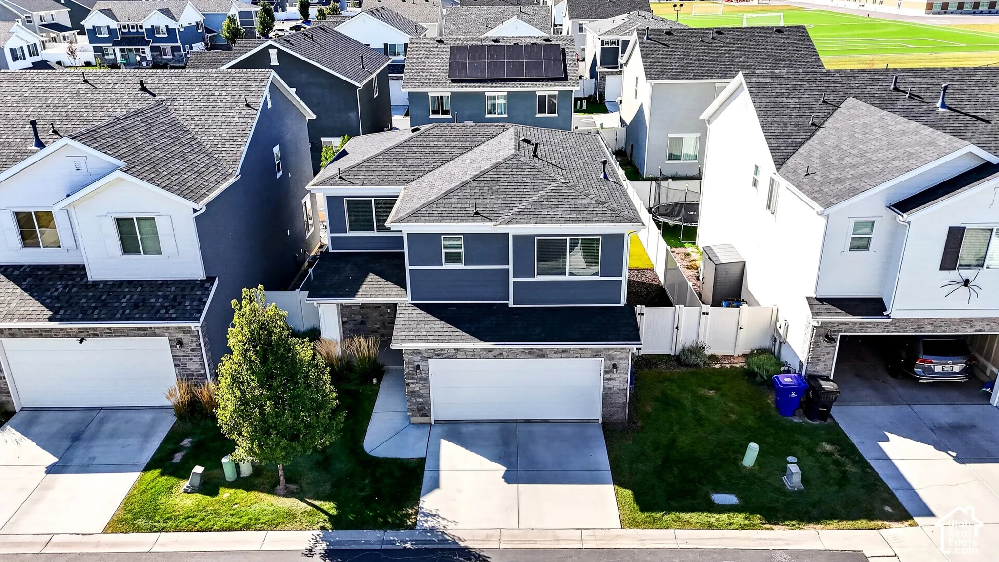 Two-story residence with a two-car garage, stone facade accents, and a front yard featuring a tree and green space