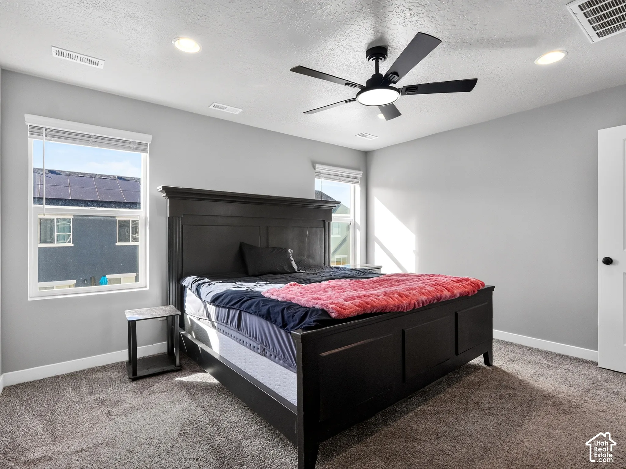 Recessed lighting, ceiling fan with integrated light, multiple windows, light gray wall finish, and gray carpet flooring