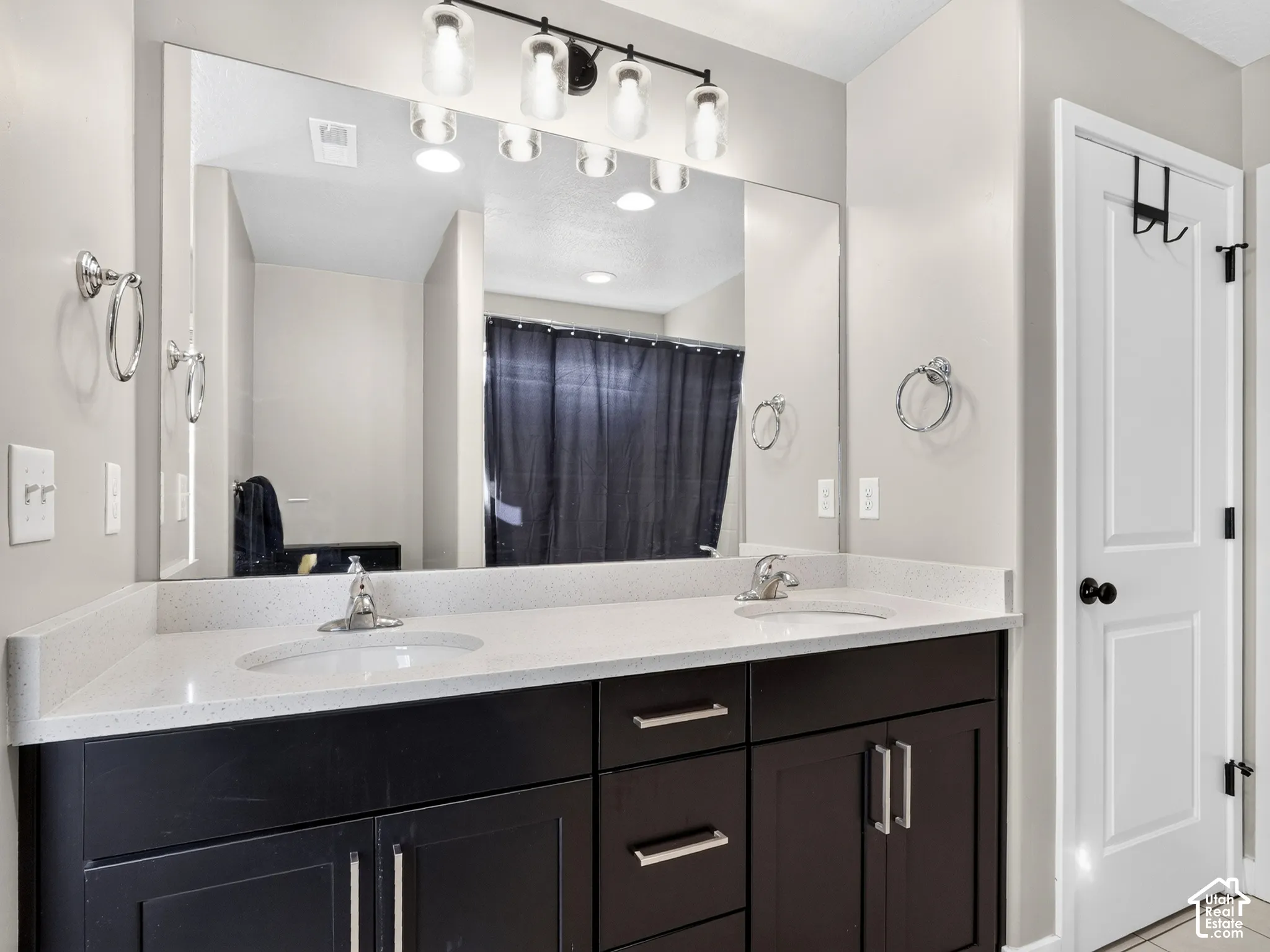 Dual vanity with integrated sinks, light-toned countertop, dark wood-finish cabinetry, and chrome fixtures