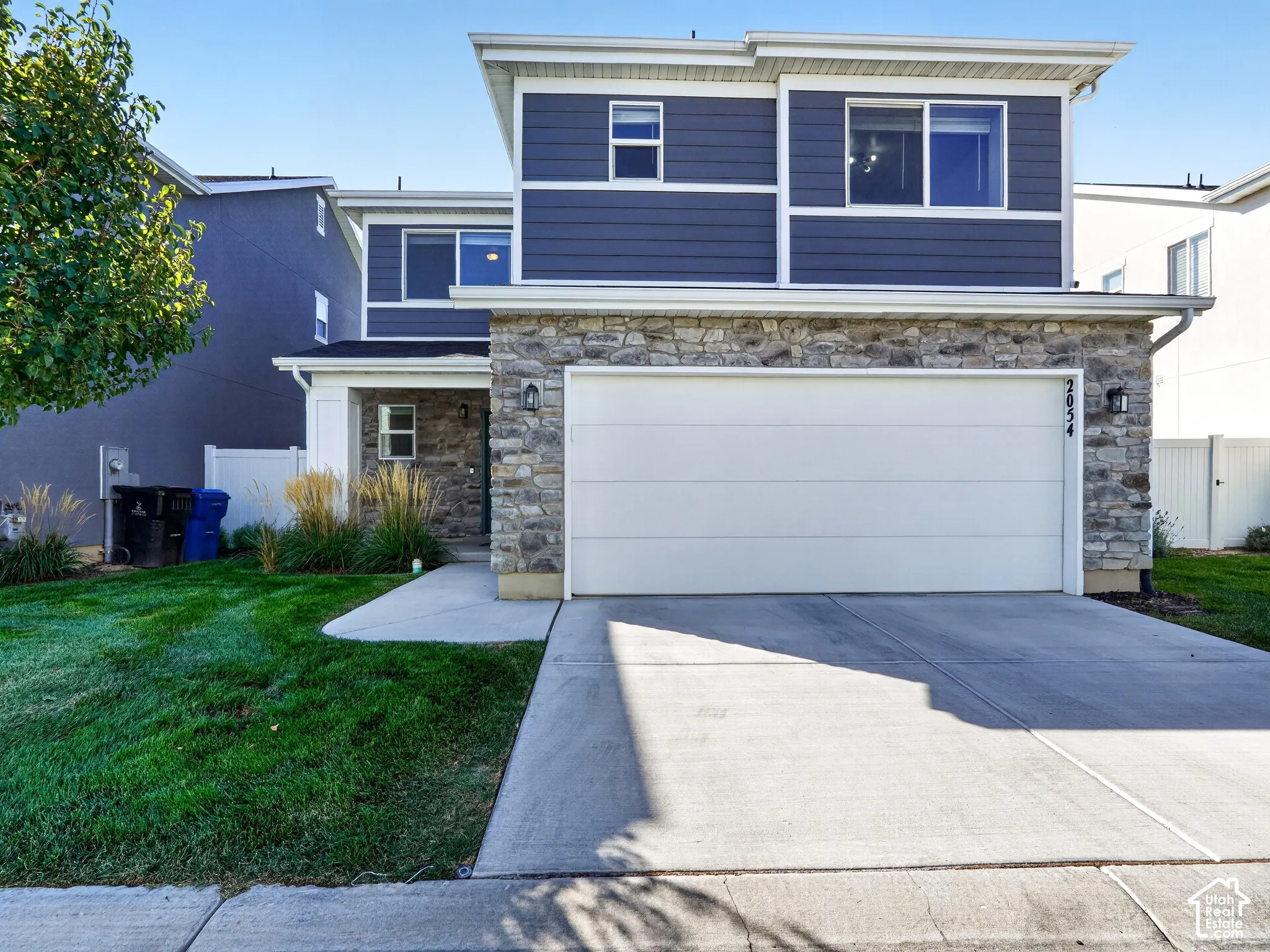 Two-story residence featuring stone and siding exterior, an attached two-car garage, and a concrete driveway