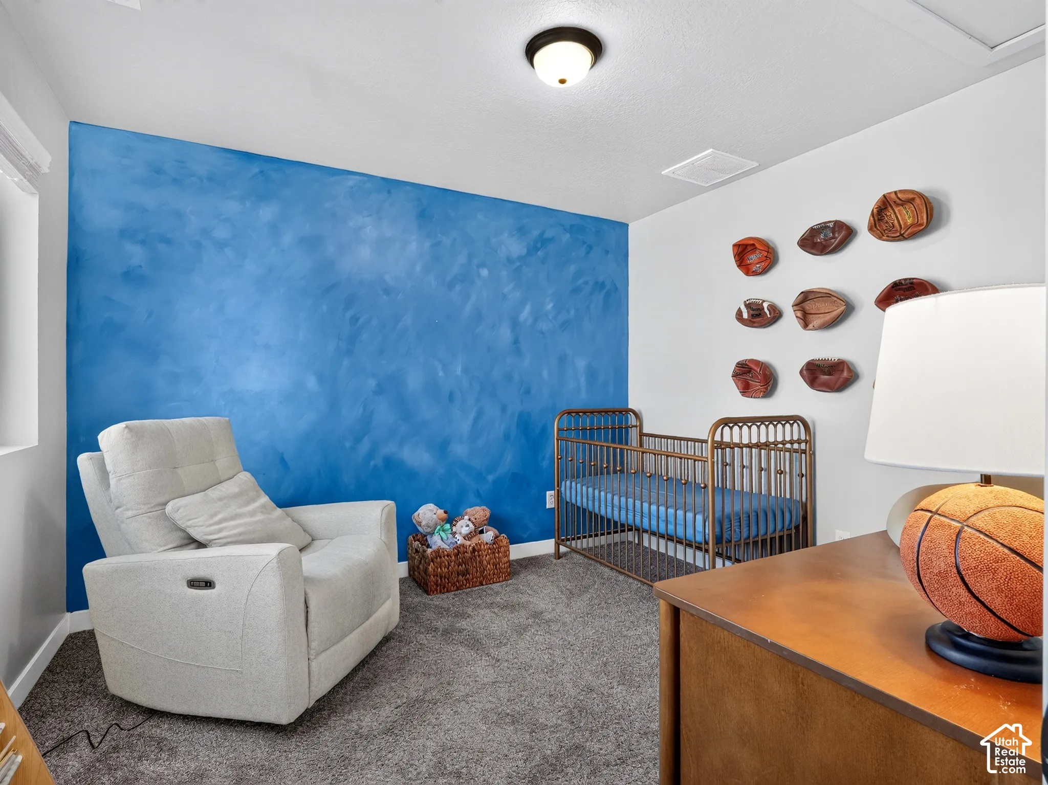 Textured accent wall, neutral carpeting, and ceiling-mounted light fixture
