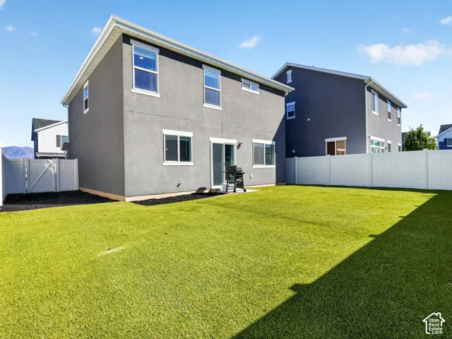 Expansive backyard with artificial turf, vinyl fencing, and a concrete patio