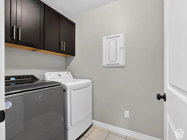 Dark wood-finish cabinetry with silver-tone pulls, light wood-finish shelving, and tiled flooring