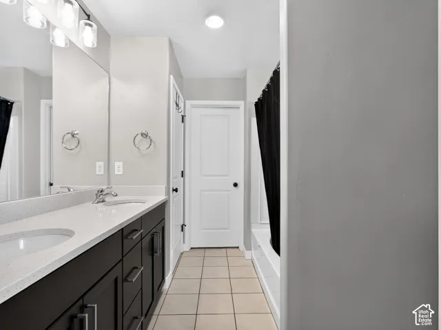 Dual sink vanity with dark wood-finish cabinetry, light-colored countertops, and chrome fixtures