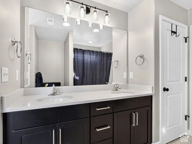 Dual vanity with integrated sinks, light-toned countertop, dark wood-finish cabinetry, and chrome fixtures
