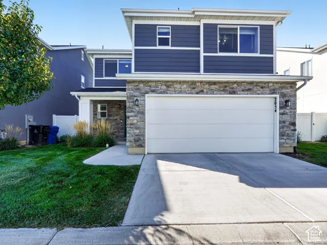 Two-story residence featuring stone and siding exterior, an attached two-car garage, and a concrete driveway