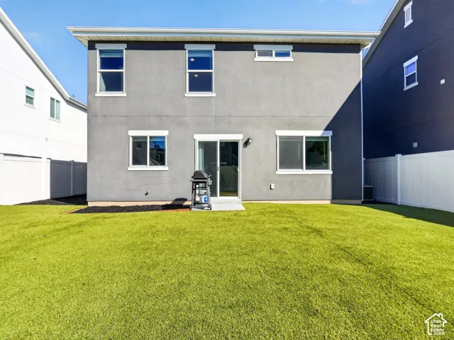 Expansive backyard featuring a manicured lawn, durable white vinyl fencing, and a concrete patio