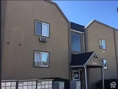 Multi-unit building with a neutral-toned exterior, gabled rooflines, and multiple windows