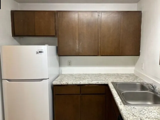 Kitchen featuring wood-finish cabinetry, light-toned countertops, and a double basin sink