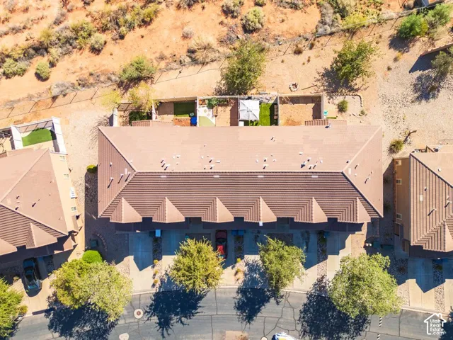 Terracotta tile roofing, multi-car driveway, mature trees, desert landscaping, and fenced backyard with artificial turf