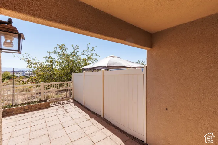 Paved patio with a white perimeter fence, stucco exterior, and an exterior wall lantern