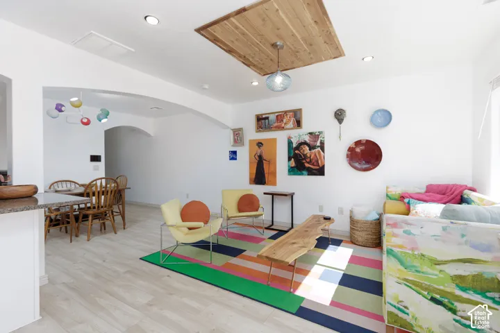 Recessed lighting, wood-finish flooring, and a decorative wood ceiling panel with a pendant light