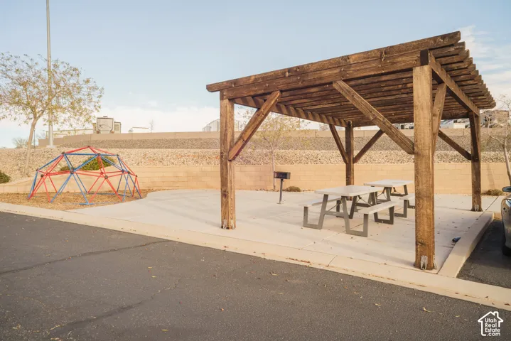 Wood pergola with concrete pad, two picnic tables, and a built-in barbecue grill
