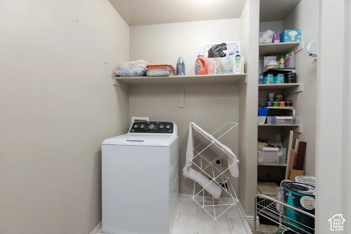 Recessed lighting illuminates a laundry area featuring a built-in shelf and an integrated storage nook with multiple shelves