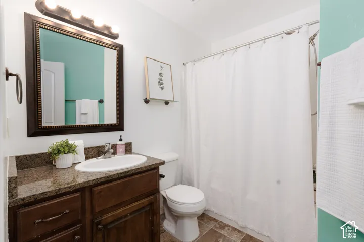 Bathroom featuring a dark wood-finish vanity, light-toned countertop, framed mirror, and a white toilet