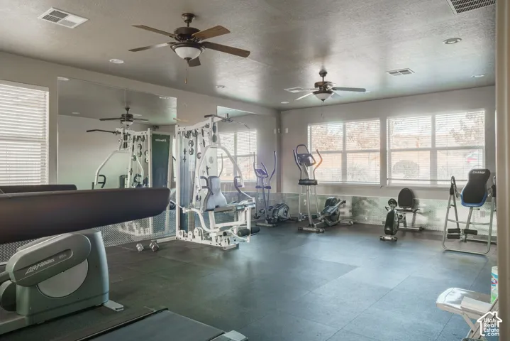 Dedicated fitness room featuring rubber flooring, full-wall mirrors, and multiple windows with blinds