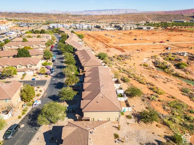 Community setting featuring residential buildings, paved streets, and a natural desert landscape with distant mountains