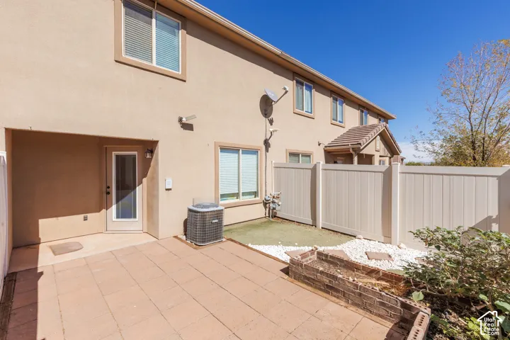 Paved patio area, brick planter, artificial turf, white rock landscaping, and vinyl fencing