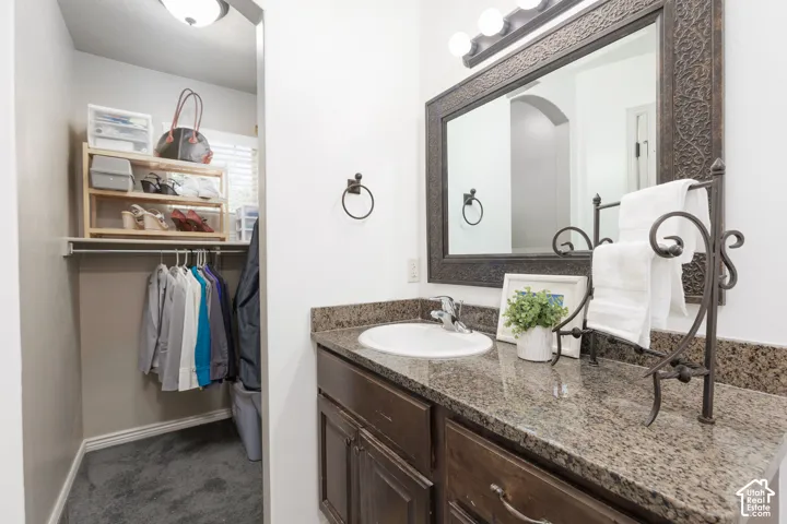 Dark wood-finish vanity with an integrated sink, granite countertop, and an ornate framed mirror