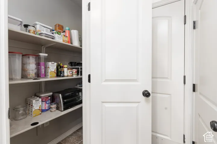Spacious pantry with adjustable shelving, white painted interior, and durable tile flooring
