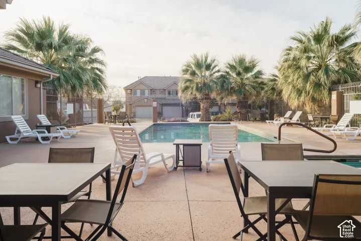 Outdoor swimming pool with surrounding concrete decking, mature palm trees, and perimeter fencing