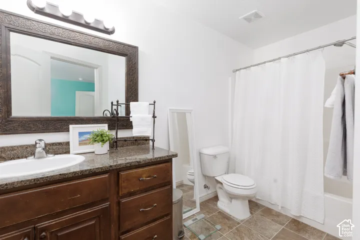 Vanity with an undermount sink and dark countertop, framed mirror, built-in cabinetry, and tile flooring