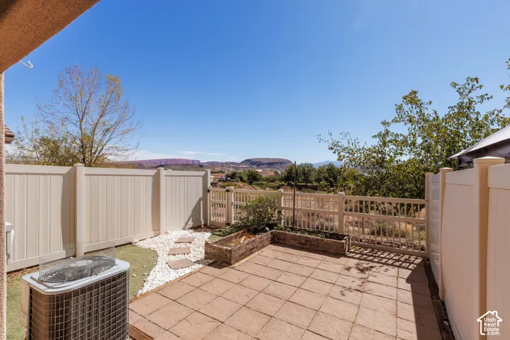 Paved patio area, raised garden bed, white privacy fencing, and mountain scenery