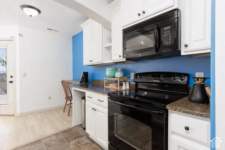 White cabinetry with dark hardware, black range, and built-in microwave