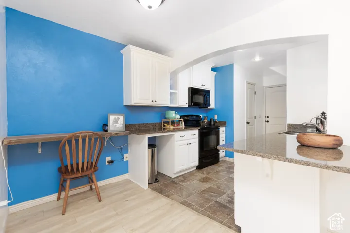 Kitchen featuring white cabinetry, stone countertops, black appliances, and a tiled floor