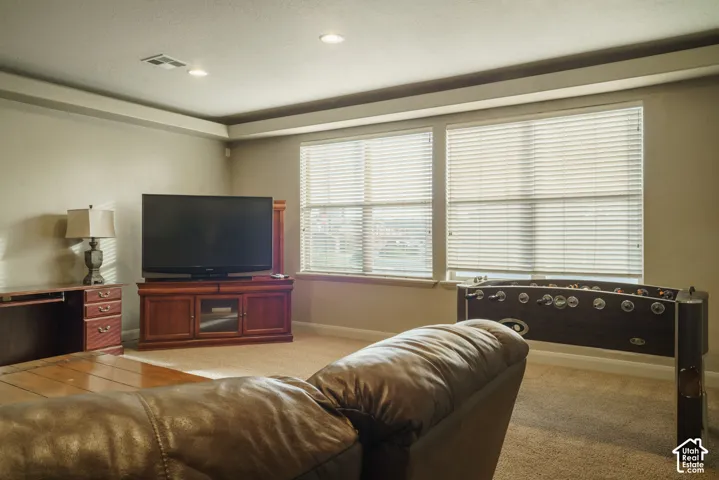 Recessed lighting, tray ceiling, two windows with blinds, and neutral wall tones