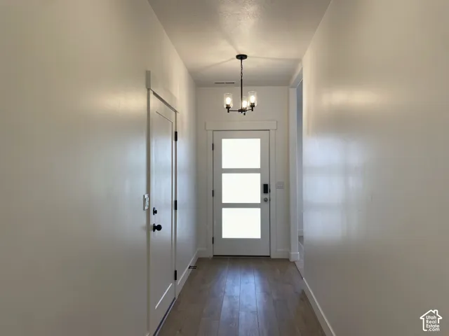 *COMPARABLE HOME, EXAMPLE OF LISTING AFTER COMPLETION.Entryway featuring wood-finish flooring, a modern three-light chandelier, and a white entry door with frosted panels
