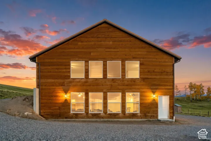 Exterior: Walls of windows glow on the gable end at dusk.