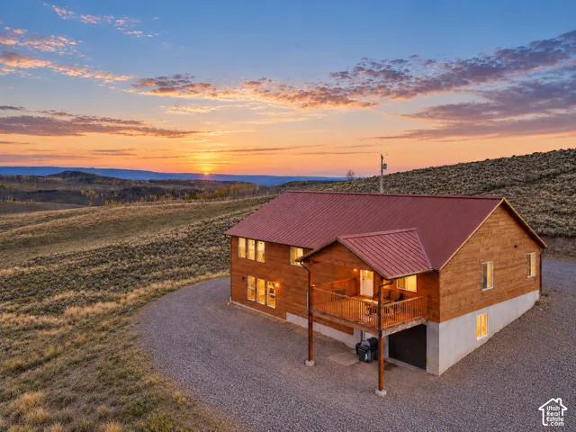 Exterior: The cabin sits on 2.25 open acres at roughly 9,500 feet, with the covered deck and walk-out main level facing a high-country sunset.